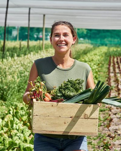 fresh produce coming right up. portrait of an attractive young woman carrying a crate full of vegetables outdoors on a farm.